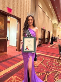 a woman in a purple dress holding a certificate