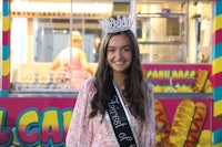 a girl wearing a sash in front of a food truck